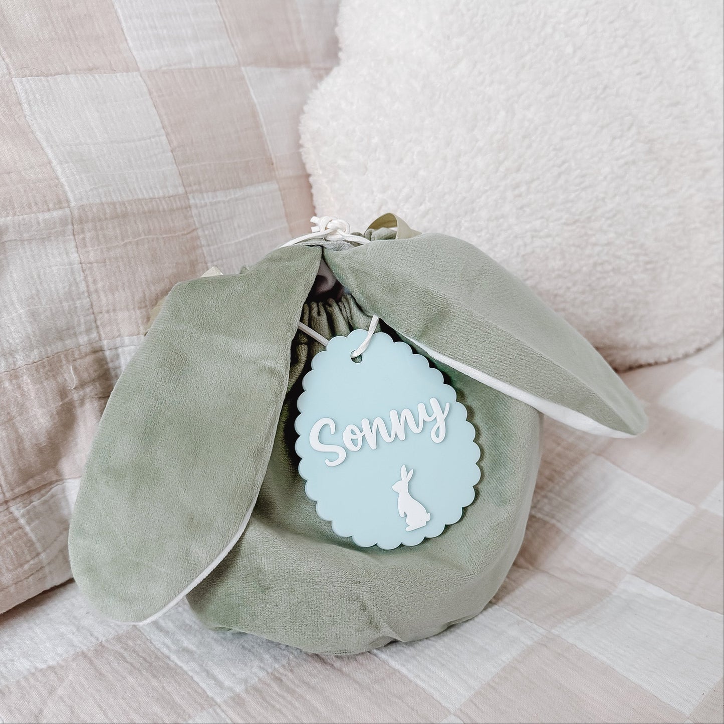 Green plush toy with a 'Sonny' tag on a checkered fabric background