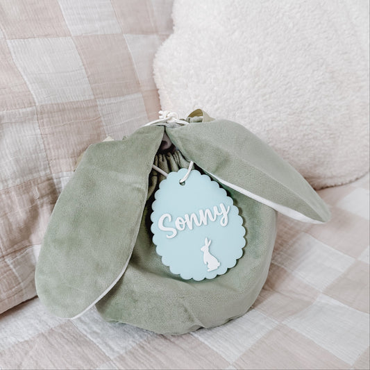Green plush toy with a 'Sonny' tag on a checkered fabric background