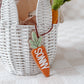 Carrot-shaped toy with 'SONNY' on it in front of a white basket.